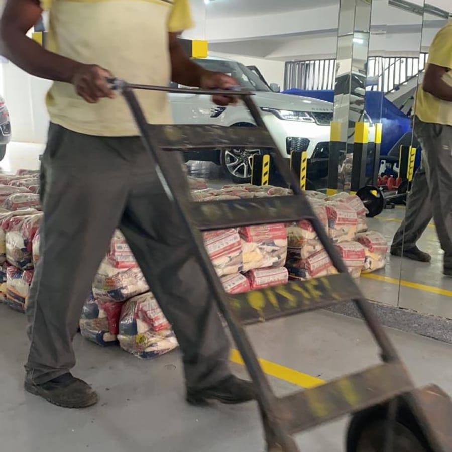 Voluntário transportando cestas básicas de carrinho